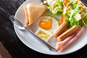 The American Breakfast  toast bread ,butter, fried egg ,sausage,  hams and salad .