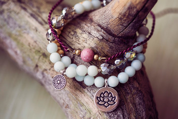 Three natural mineral stone beads bracelet on wooden background - obrazy, fototapety, plakaty