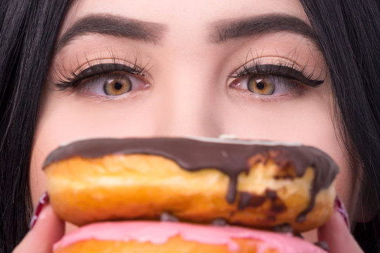 a portrait of a plus-size model covered her face with donuts and looking at them close-up photos