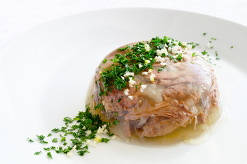 jellied calve foot broth with beef decorated with green herbs and garlic