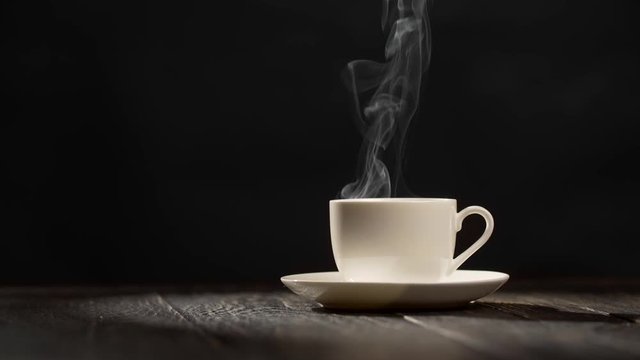Coffee cup on dark vintage wooden background with steam. UHD, 4K