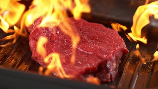 Super slowmotion footage of throwing fresh beef meat and seasoning on ignited pan, 1000fps 4k