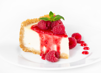 Piece of cheesecake with raspberries and mint on white background.