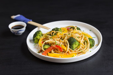 Asia food. Stir fry udon noodles with vegetables on the black table, cooked in wok