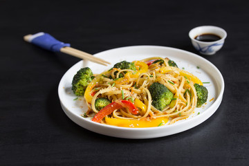 Asia food. Stir fry udon noodles with vegetables on the black table, cooked in wok