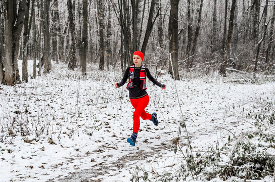 Young woman athlete in red leggings runs in the winter forest. Winter sports. Extreme running.