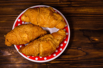 Plate with croissants on a wooden table. Top view