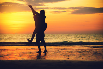 Fototapeta na wymiar Asian lovers happy on the beach with a beautiful sunset in background man lifting the woman.Travel relax on the beach vacation. in summer