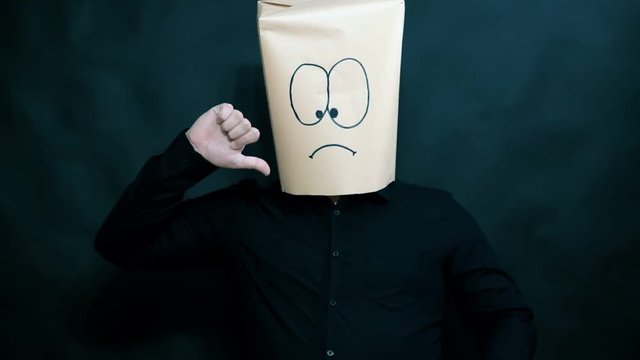 Emotion concept. A man shows thumbs down. It is not pleasant. On the face expressed sadness and sadness.