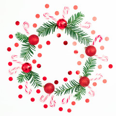 Christmas frame of fir branches and red balls decoration with confetti on white background. Festive background. Flat lay, top view