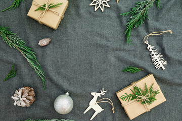 New Year winter frame concept. Christmas Nordic decorations with evergreen tree branches and gift boxes on cloth background. Flat lay, top view.
