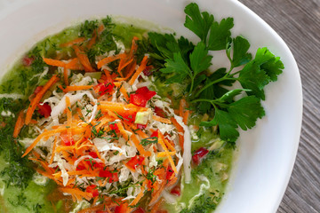 Vegetarian dish. Vegan green cabbage soup made from Chinese cabbage, carrots, peppers, tomatoes, avocados, pumpkin seeds and lemon juice, garnished with parsley.