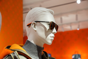 Mannequin's white head in an orange-rimmed sunglasses and grey turtleneck