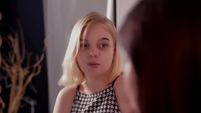 Two lesbians are talking in a bright spacious room, two cute friends are discussing their boyfriends, blonde and brunette are sitting on the armchairs, a room in a minimalist style