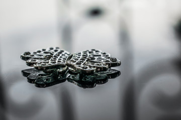 Glossy, reflective background decorated with silvery small accessories with white stones-rhinestones. Little crowns, tiaras. Jewelry for women and brides.