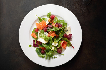 Fresh salad with salmon and cheese on white plate
