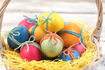 Basket with Easter eggs on white wooden background