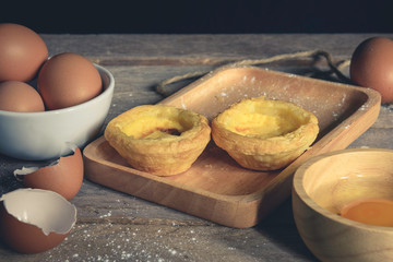 Egg tart on a wooden plate, the background is out of focus.