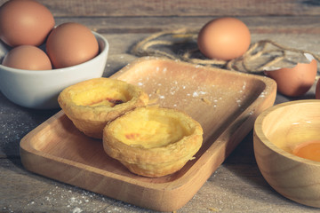 Egg tart on a wooden plate, the background is out of focus.