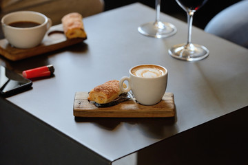 cup of coffee with a bun on a wooden stand