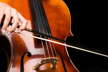 Fototapeta premium Young girl playing the cello on isolated black background
