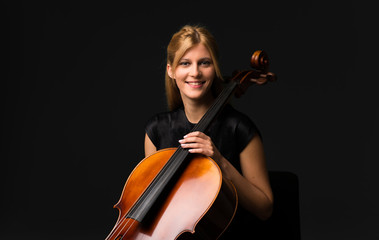 Young girl playing the cello on isolated black background © luismolinero