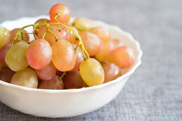 Grapes in a porcelain plate. Ripe pink Muscat grapes.