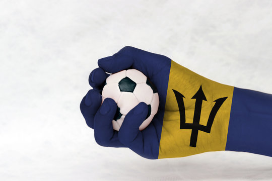 Mini ball of football in Barbados flag painted hand on white background. Concept of sport or the game in handle or minor matter.