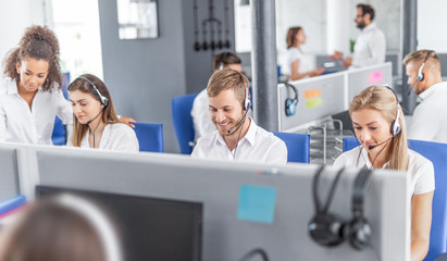 Call center worker accompanied by his team. - obrazy, fototapety, plakaty