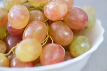 Grapes in a porcelain plate. Ripe pink Muscat grapes.
