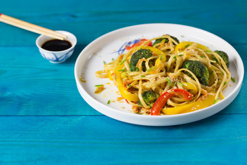 Asia food. Stir fry noodles with vegetables on a blue wooden backgound, cooked in wok