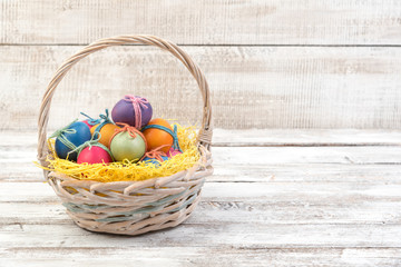 Easter eggs in basket on a white wooden background, copyspace