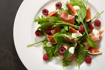Fresh salad with prosciutto on plate