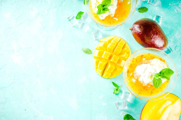 Tropical mango floating margarita cocktails with coconut ice cream, light blue background copy space