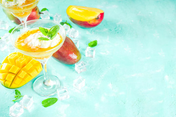 Tropical mango floating margarita cocktails with coconut ice cream, light blue background copy space