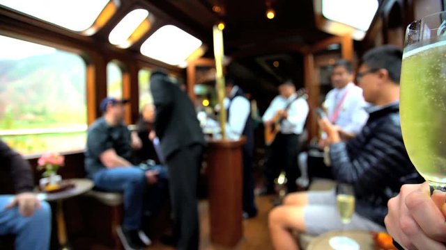 Tourists drinking Champagne in the dining carriage with musicians playing on the Machu Picchu Inca train South America