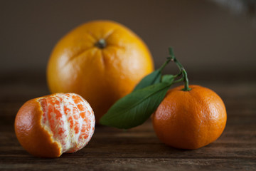 tangerines and grapefruit lie on a wooden table