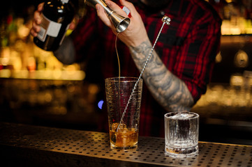 Bartender hand pouring strong alcohol into a cocktail glass
