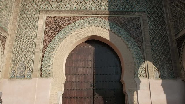 Camera tilt up view from bottom to top of Bab Mansour Gate wooden door in Meknes, Morocco