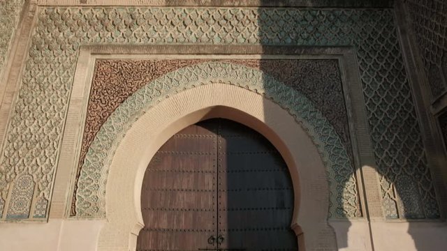 Camera tilt down push in forward view from top of Bab Mansour Gate wooden door in Meknes, Morocco