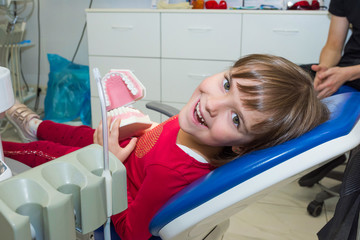 A happy girl with a jaw mock in a dentist’s office.