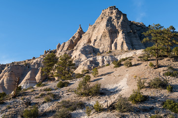 High, steep mountain peak with hoodoo rock formations and ponderosa pine trees at Kasha-Katuwe Tent Rocks National Monument, New Mexico