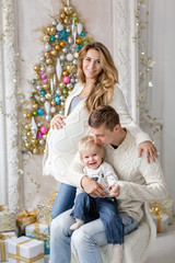 Fototapeta na wymiar Young parents fool around and play with little son. Happy family having fun at home. Christmas morning in bright living room. Father, pregnant mother and their baby boy. Happy new year. Upside down