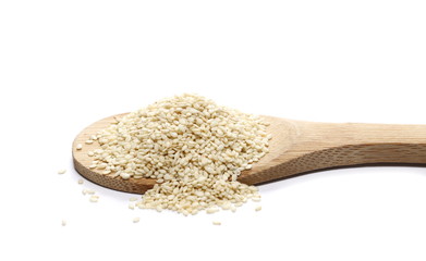 Pile sesame seeds and wooden spoon isolated on white
