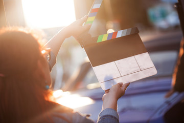 Filming on location. Woman holding a clapperboard in front of the camera, the filming process.