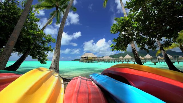 Canoe boats Palm trees Overwater Bungalows in tropical aquamarine lagoon a luxury vacation resort in Bora Bora South Pacific French Polynesia