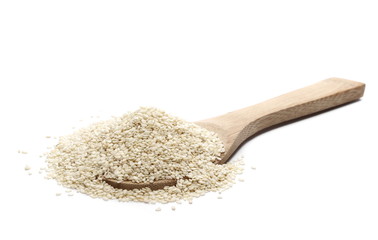 Pile sesame seeds and wooden spoon isolated on white