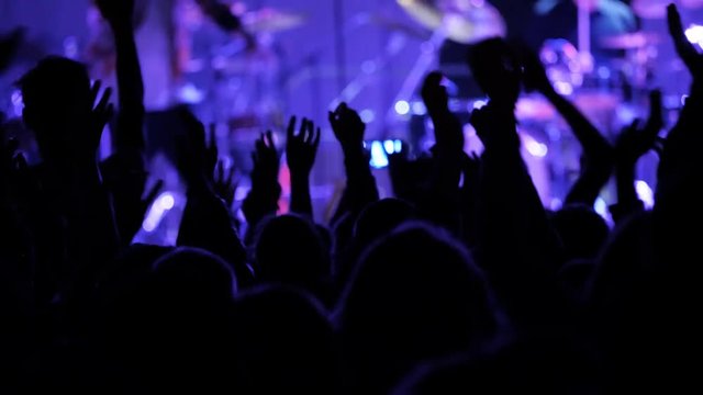 Crowd hands up and stage lights at night concert