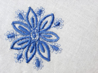 embroidered blue flower on white fabric