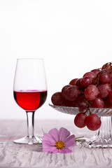 Red wine in a glass and grapes on a light background